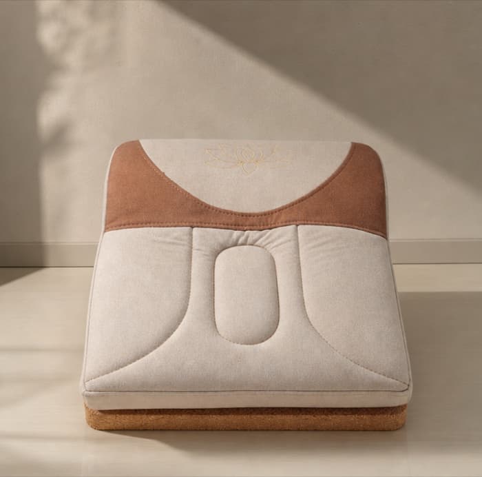 The Lotus Seat in three-quarter elevation: a cream cotton-linen cushion with a terracotta yoke and gold lotus embroidery, seated on a solid cork base
